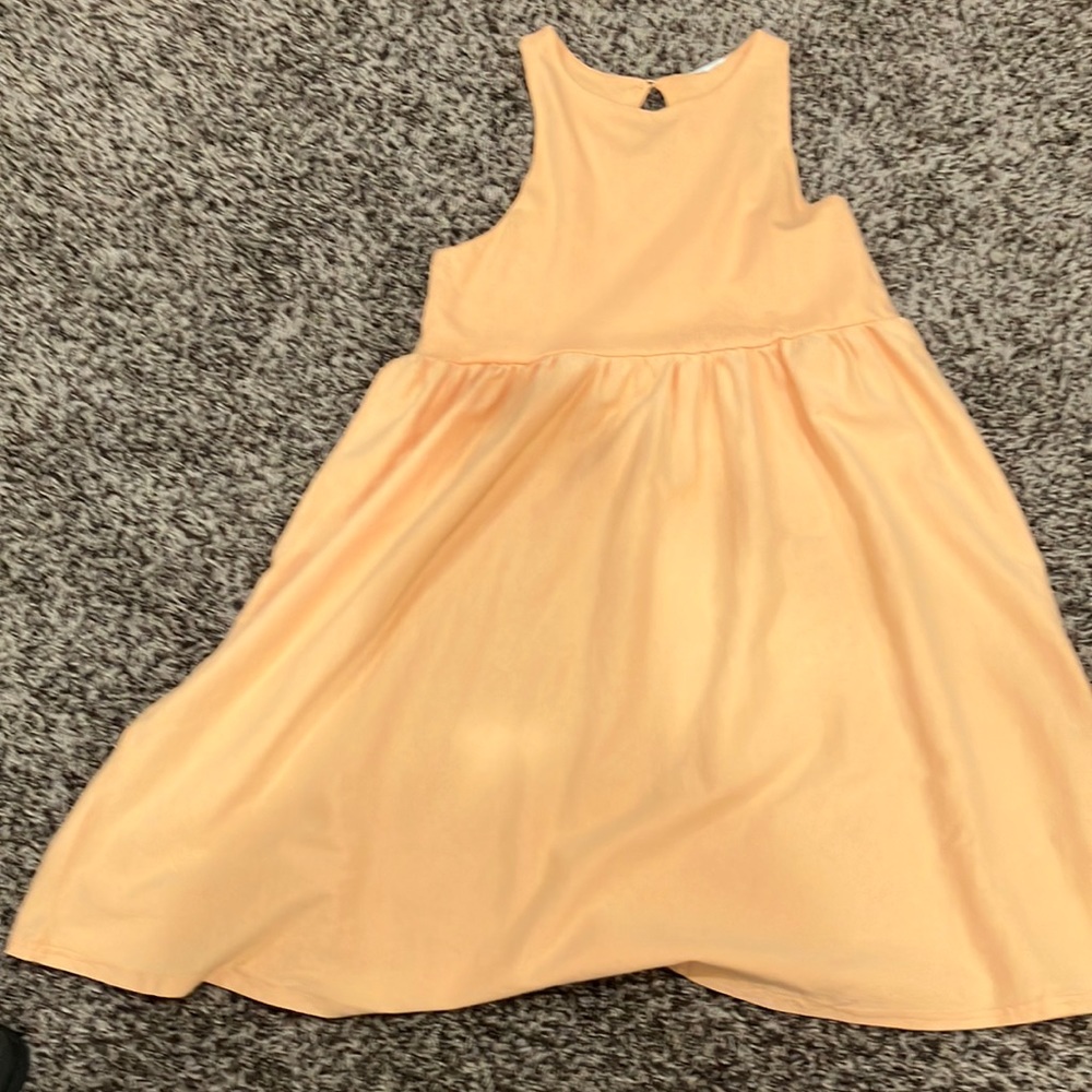 This dress is an orange dress. it has a small orange button on the back